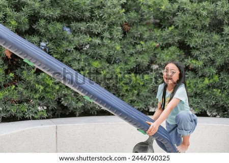 Joyful Asian girl having enjoy and fun playing on a zip line in an adventure park outdoors on the playground.