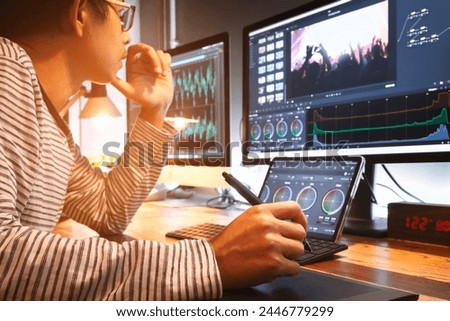 filmmaker, movie video editor or colorist, working with footage or video on his personal computer by pen tool and tablet, in his creative office studio. post-production process.	