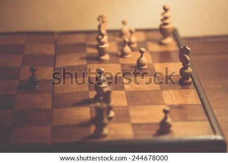 Old chess pieces on a wooden chessboard