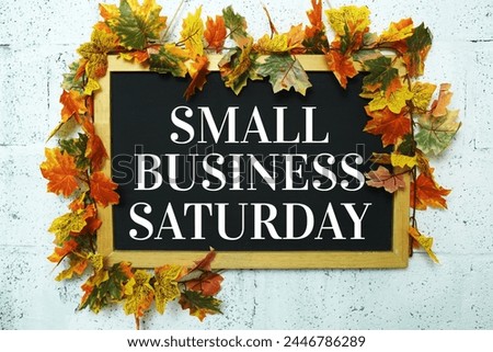 Small Business Saturday typography text on wooden blackboard hanging with maple leaf decoration