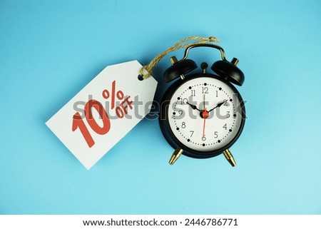 Top view of Sale 10% text on tag sale with black alarm clock flat lay on blue background