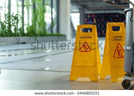Two Yellow caution wet floor sign on Wet floor  and Cart with cleaning equipment, copy space