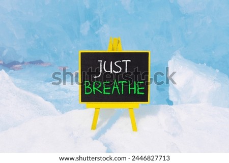 Just breathe and psychological symbol. Concept words Just breathe on beautiful yellow black blackboard. Beautiful blue ice background. Business psychological and Just breathe concept. Copy space