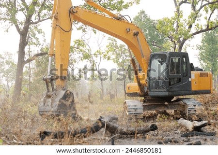 A backhoe is digging up trees, reclaiming the forest.
