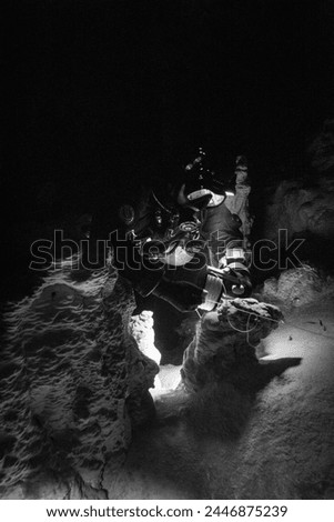 Cave diver laying line on a stalactite - black and white edgy photo