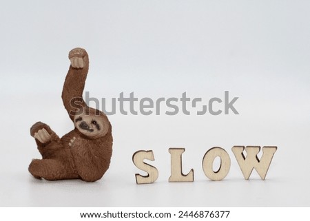 miniature figurine toy of a sloth with the inscription "slow"