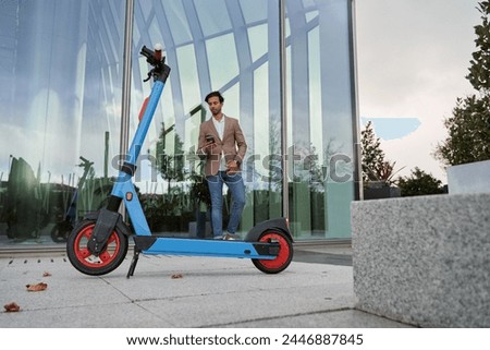 indian businessman walking with his electric scooter in a business district. green urban transport concept