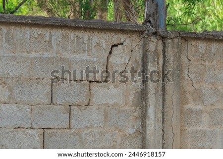 Damage in wall in form of diagonal cracks indicates that soil in this place has been subjected to some kind of impact, has lost its load-bearing capacity, thereby support of foundation has subsided. Royalty-Free Stock Photo #2446918157