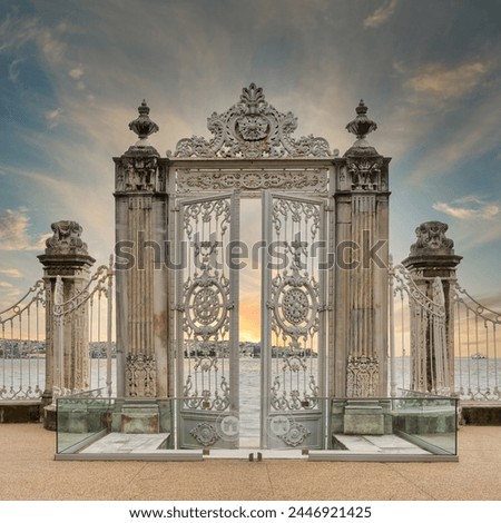 Sunrise shot of pair of half closed elaborately decorated white painted metal gates leading to the opulent Dolmabahce Palace in Istanbul, Turkey, and offering stunning views of the Bosphorus Strait Royalty-Free Stock Photo #2446921425
