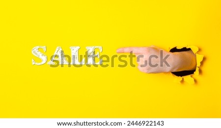 A hand pointing to the word sale on a yellow background. Concept of urgency and excitement, as if the sale is happening right now and the viewer should take advantage of it