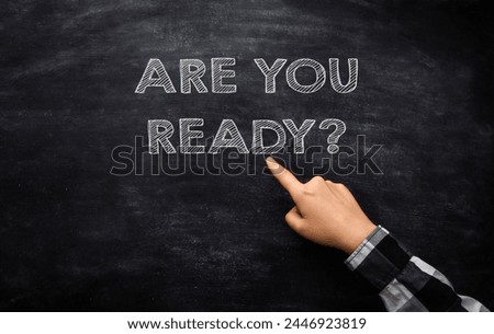 A hand pointing at a chalkboard with the words Are you ready written below it, illustrating a business concept. Royalty-Free Stock Photo #2446923819