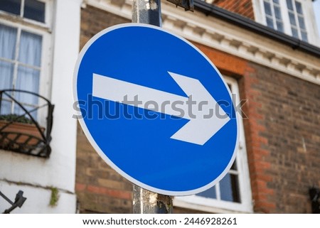 A one way road traffic sign, white arrow on blue