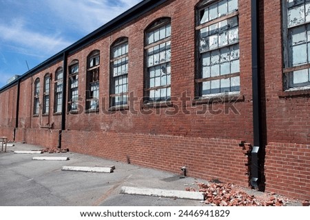 Abandoned brick industrial building with broken and weather worn windows with new guttering  Royalty-Free Stock Photo #2446941829