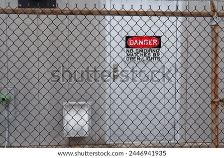 Danger sign through a chain link fence