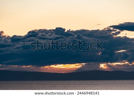 Gloomy weather with scenic color. Beautiful overcast dark clouds on summer evening. Golden sky. Dramatic storm. Sunlight. Ocean.Foreboding impending dangerous threat. Murky heaviness. Dreary darkness. Royalty-Free Stock Photo #2446948141