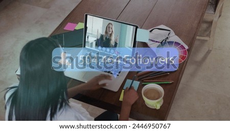 Young biracial woman engages in a video call on her laptop. She appears focused on growing her social media presence, as indicated by the follower count.