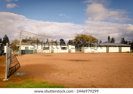 Empty school baseball field on a sunny day with one story school buildings in the background