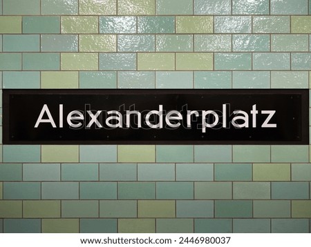 Alexanderplatz station sign in Berlin. The location signage of the public transportation is part of the underground. The tiled wall is in green and teal color.