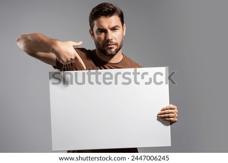 Man holds sign with copy space. Placard ready for copy space product. Sign to your copy space text. Man showing blank sign board on studio background, pointing finger. Empty copy space blank board.