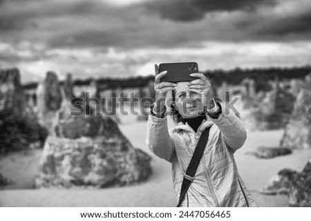 Female photographer taking pictures of sand and rocks in Pinnacles Desert.