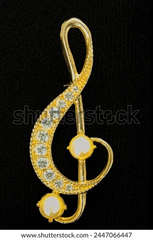 Ladies gold treble clef broach on white background Royalty-Free Stock Photo #2447066447