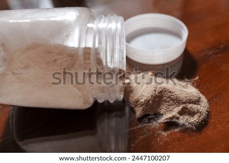 Ground pepper in a jar coming out on a brown wooden table, concept photo, stock photo.