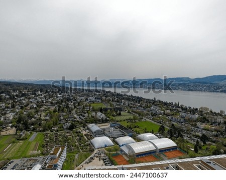 Aerial view over Swiss City of Zürich with woodland, Lake Zürich and Swiss Alps in the background on a cloudy spring day. Photo taken April 7th, 2024, Zurich, Switzerland.