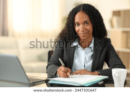 Front view portrait of a tele worker signing contract or filling form looking at you at home