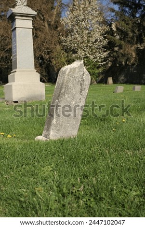 A simpe worn and weathered gravestone standing in the old cemetery with a blank epithet. Royalty-Free Stock Photo #2447102047