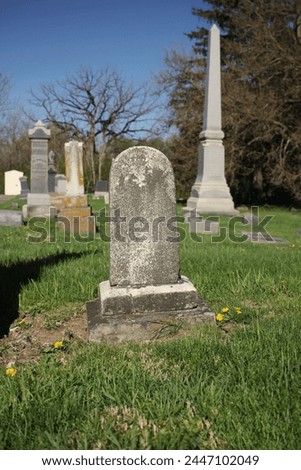 A simpe worn and weathered gravestone standing in the old cemetery with a blank epithet. Royalty-Free Stock Photo #2447102049