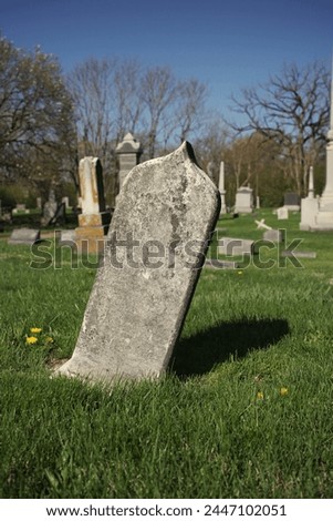 A simpe worn and weathered gravestone standing in the old cemetery with a blank epithet. Royalty-Free Stock Photo #2447102051