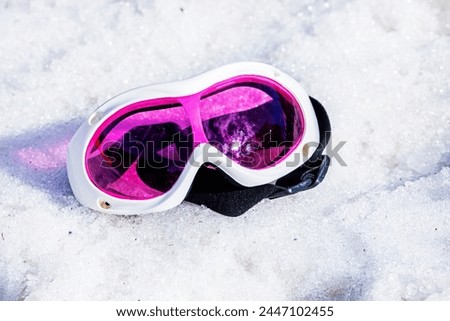 pink lying mask lies on a wet snowy slope on a sunny day. Winter snow season. Active holiday with family