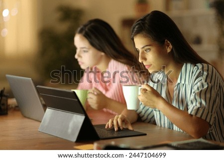Two tele workers drinking and working online in the night at home Royalty-Free Stock Photo #2447104699