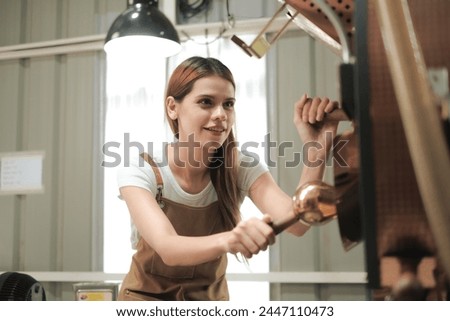 White woman craftsperson using roasted coffee beans machine with smile of happiness, Woman work in roasted coffee beans manufactory. Royalty-Free Stock Photo #2447110473