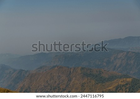 The mountains are covered in a haze, giving the scene a somber and moody atmosphere. The misty air adds a sense of mystery and depth to the landscape, making it feel almost otherworldly Royalty-Free Stock Photo #2447116795