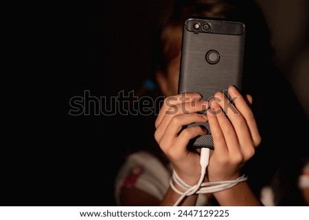 Computer, media, game, network, digital, technology, gadget  and  internet addiction concept. Portrait of young beautiful girl with tied hands using smartphone at night. Copy space for design.