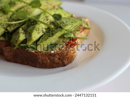 Healthy Nutrition Stock Photo. Detailed Image Of Toasted Bread With Sauce And Topped With Slices of Avocado and Fresh Peas Microgreens 
