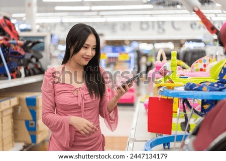 Mother woman carefully examines a modern, decision making stroller in spacious baby store, mindful parent, seeking quality and safety in children products family planning, baby care products, shopping Royalty-Free Stock Photo #2447134179