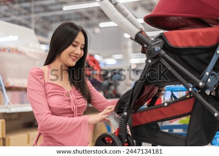 Mother woman carefully examines a modern, decision making stroller in spacious baby store, mindful parent, seeking quality and safety in children products family planning, baby care products, shopping Royalty-Free Stock Photo #2447134181