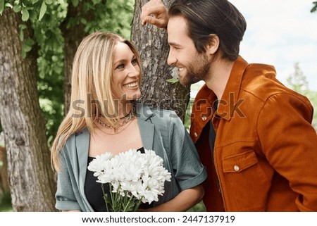 A man holds a beautiful bouquet of flowers next to a woman, emphasizing the romance between them. Royalty-Free Stock Photo #2447137919