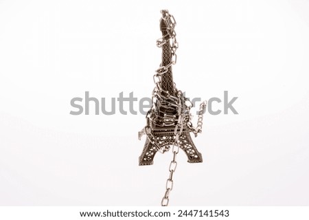 Little model Eiffel Tower  in chains on a white background