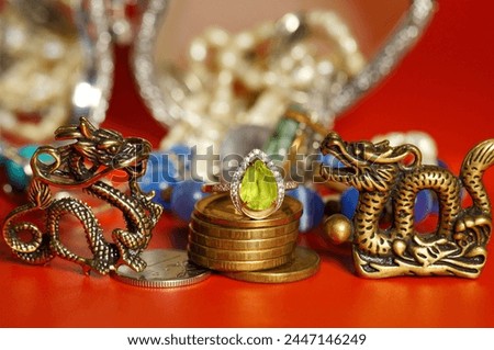 A statuette of a Chinese dragon with coins and a green ring.