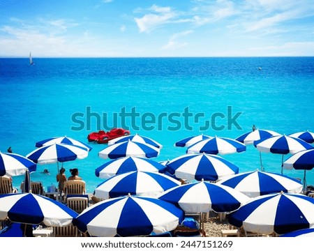 turquiose water of cote dAzur over striped beach umbrellas, France, retro toned Royalty-Free Stock Photo #2447151269