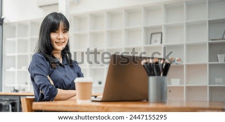 Professional young businesswoman sitting confidently at a cafe table with her laptop, ready for a productive work session.