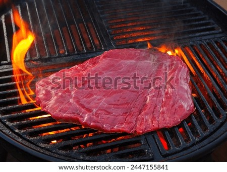 Traditional raw barbecue flanksteak steak as close-up on a charcoal grill with fire  Royalty-Free Stock Photo #2447155841