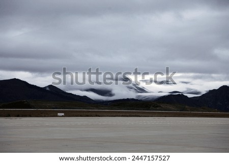 Landscape photo view of the Jiuzhaigou airport tarmac with no plane with the rnage mountains chain in teh background inthe humid cloudy above clouds in altitude in Sichuan China