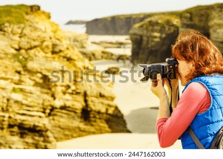 Tourist woman taking travel photo from sea coast landscape, cliff formations on Cathedral Beach in Galicia Spain. Playa de las Catedrales, As Catedrais in Ribadeo, province of Lugo.