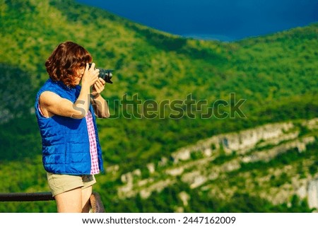 Tourist mature woman take travel picture from mountain hill landscape in France.