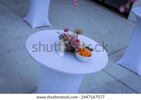A formal table setting with snack food with pink flowers and tea lamp with cheese puffs (Cheetos Brand) crisps and pretzels with an informal feel. 