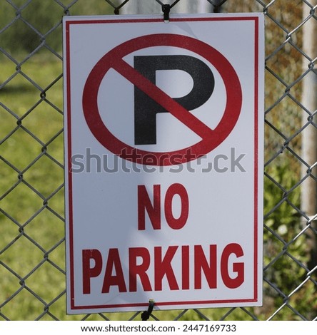 A no parking sign on a chain link fence.